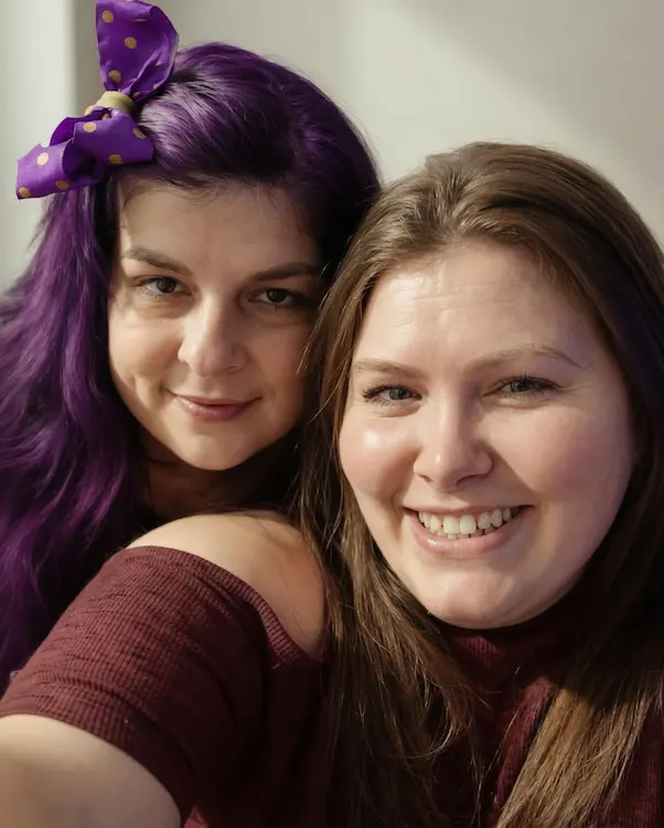 Two smiling cleaning professionals representing the heart and soul of Em & L Cleaning Services in a warm, welcoming eco-friendly setting that suggests trust and care